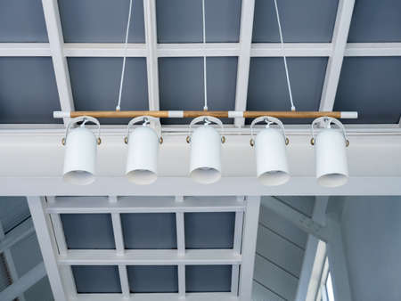 five spotlight hanging  in cafe. Modern ceiling lamps set under the stylish construction building in living room in the white house. Stretch ceiling white and complex shape.の写真素材