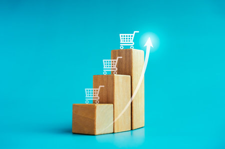 Shining rise up arrow on wooden blocks, bar graph chart steps with shopping cart icons on blue background, inflation in e-commerce business growth, marketing, online shopping increase trends concepts.の写真素材