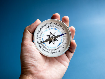 Closeup blue words "SUCCESS" on compass in businessman's hand on blue background. Business goal and success, plan and direction concepts with target as motivation.の写真素材