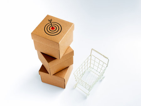 Target icon on cardboard parcel boxes stack and empty shopping trolley cart on white background....