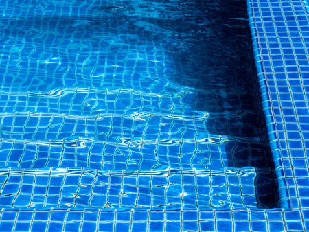 Swimming pool steps with clear water surface background, nobody. Abstract pool texture, underwater...