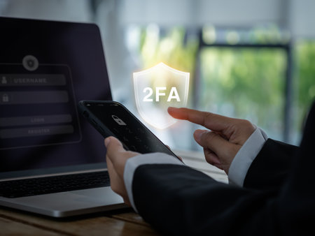 Two steps authentication concept. 2FA in shield icon showing on smart phone while businessperson press password to connect on laptop computer, Identity verification, cyber security technology.の写真素材