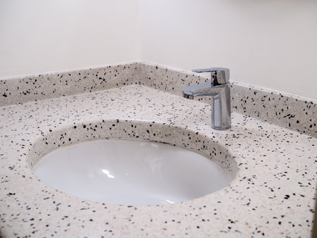 Stainless steel chrome silver tap or faucet in round shape of terrazzo tiles wash basin on white wall background. Retro style bathroom or powder room interior design.の写真素材