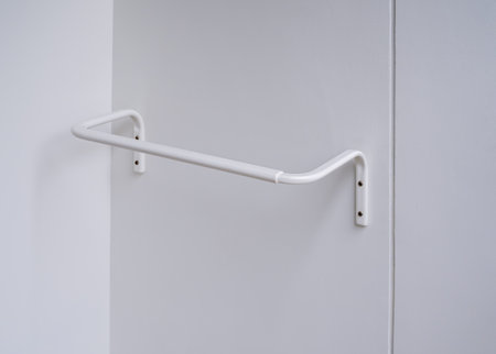 White modern clothes drying rack, curved shape on the white wall background at the terrace in hotel room. Empty white wall mounted laundry towel drying rack.の写真素材