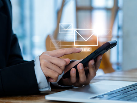 Sending Email and business marketing concepts. Fast moving of digital letters icon appearing while business person using, mobile smart phone and laptop computer at workplace, send message.の写真素材