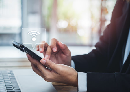 Share wifi by smart mobile phone. Sharing icon appear on cell phone holding by business people in suit, sharing wifi connection for working with laptop computer in cafe, remote working everywhere.の写真素材