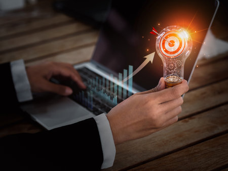 Digital marketing business success concept. Target 3d icon in creative idea light bulb holding by business person hand who working with laptop computer. Creative motivation for successful business.の写真素材