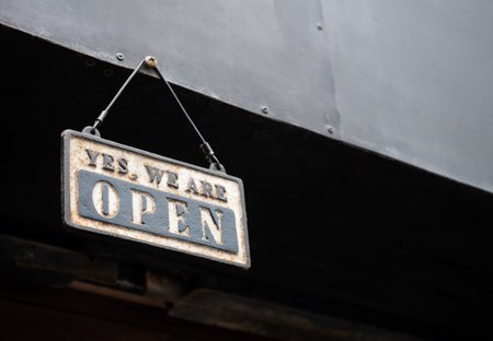 Text, Yes, we're open, vintage rusty signage hanging on the screw on the part of gray building in front of the coffee shop with copy space. Outdoor shop sign, retro style.の写真素材