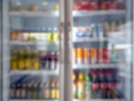 Abstract blur of freezer with many kind of drinks inside in supermarket. Blurred cold drink cooler, soft defocused of white fridge in store. Blurry refrigerator with glass background.の写真素材