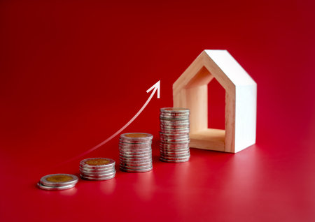 Property value, real estate investment, home price and inflation concepts. Rising up arrow growth on coin stacks as chart steps with modern wooden house model on red background.の写真素材