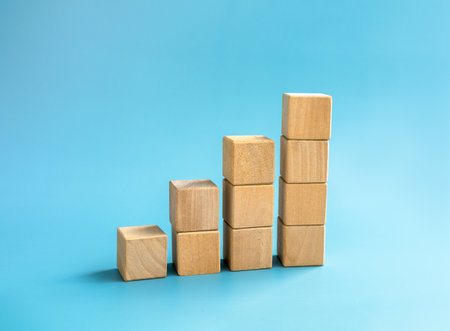Blank wooden cube blocks bar graph chart steps, isolated on blue background, investment, income, trends, inflation, business growth, economic improvement concepts. Four step eco style wood graph.の写真素材