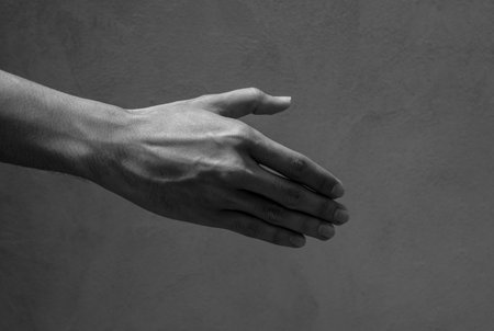A man's right hand with shake hand gesturing with nobody, black and white style. Alone human hand side view is reaching out on empty space, dark tone.の写真素材