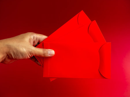 Three red envelope holding by hand isolated on red background. 3 Hongbao packets for lucky money gift in Chinese lunar, new year on January month, wedding red packet.の写真素材