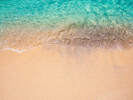 Relaxing beach scene, top view. Movement of blue sea water and wave surf on clean sandy beach ocean, sea shore, coastline, summer vacation holiday background with copy space.の写真素材