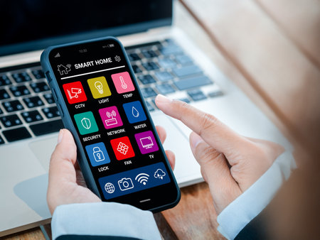 Smart home applications technology on smartphone holding in hand. Smart house app screen on mobile phone for wireless remote connection control using by business person who working with computer.の写真素材