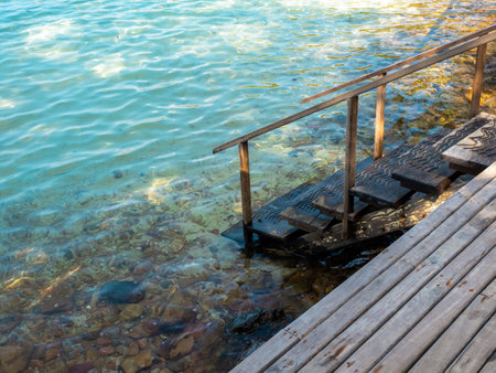 Path down to the sea. Empty wooden steps way on wood plank terrace on the beach, rocks and blue relax sea water background. Summer vacation and holiday travel concept.の写真素材