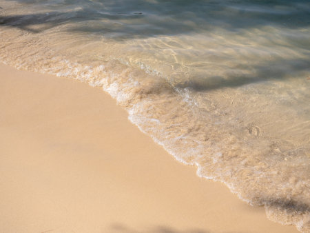 Bright beach background, movement of clear sea water and wave surf on clean sandy beach ocean,...