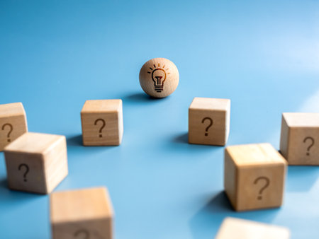 Idea light bulb icon on wood sphere near the many problems, wooden cube blocks with question mark symbol on blue background. Concept of leadership, business management and solution.の写真素材