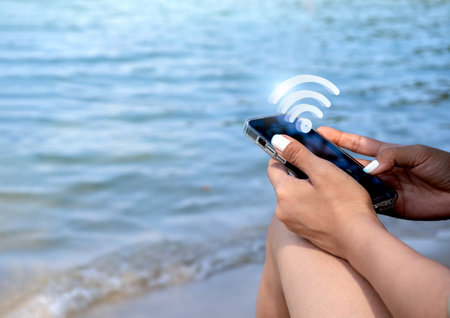 Wifi, 3d icon virtual on smart mobile phone. Wi-fi sharing symbol appear on cell phone holding by stylish female at the beach with sea and sand background with copy space. Social media lifestyle.の写真素材