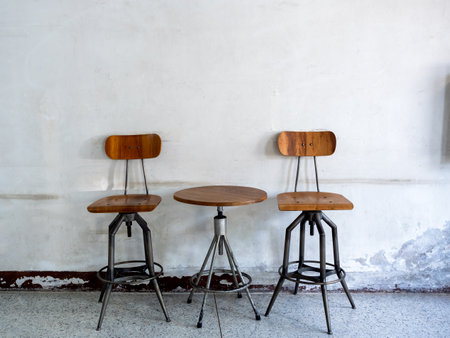 Empty vintage spinning chairs backrest, seat and round spinning side table decorated on old white wall background, loft style building interior. Swivel wood table set, wooden and black iron materials.の写真素材