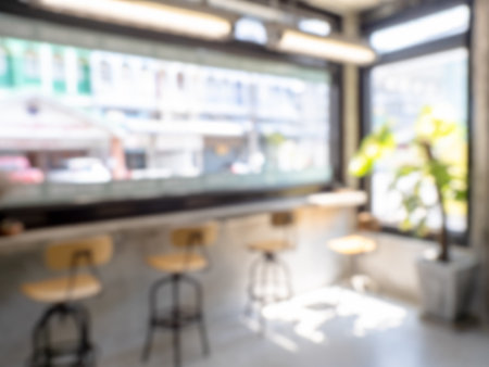 Abstract blurred modern cafe workspace, indoor interior restaurant space, loft style furniture and the large glass window with the light. Blurry backgrounds for advertising and business presentation.の写真素材