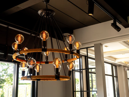 Modern chandelier in living room near glass window, loft style, vintage ceiling light or light bulbs hanging with from wooden ceiling, indoor, interior loft style building. Retro lighting decoration.の写真素材