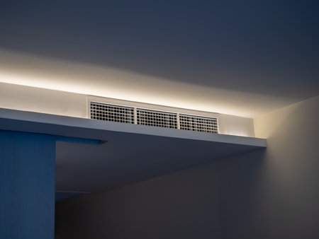 Air conditioning wall mounted ventilation system on ceiling in the white hotel room with dim light. Hotel room air ventilation grill on the wall.の写真素材