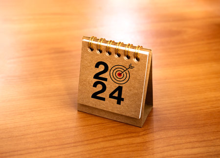 Happy new year 2024 banner background. 2024 numbers year with target icon on beige small desk calendar cover standing on wood table, minimal style. Business goals plan and success concepts.の写真素材