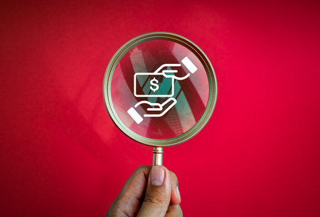 Searching, stop corruption and anti corrupt concept. Corruption icon in a luxury gold magnifying glass in people's hands isolated on red background, minimal style. Found hidden illegal act.の写真素材