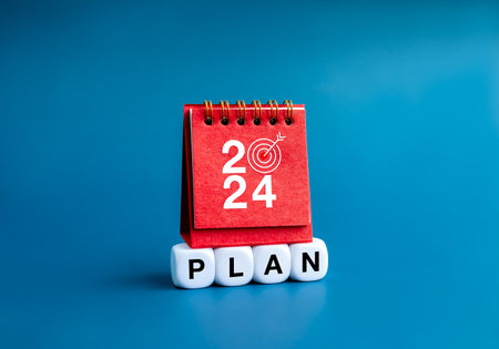 Happy new year 2024 banner background. 2024 numbers year on red small desk calendar cover standing on on white blocks with word "PLAN"  isolated on blue background. Business goal and success concepts.の写真素材