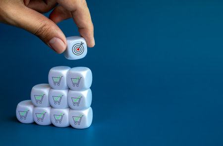 Target icon hold by hand, put on top of white cube block stack as a growth graph steps with shopping cart and check mark icons on blue background with copy space. Sales increase and profit concept.の写真素材