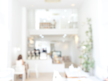 Abstract blurred modern cafe background, white indoor interior of minimal white coffee shop with lighting and decoration furniture. Blurry backgrounds for advertising and business presentation.の写真素材