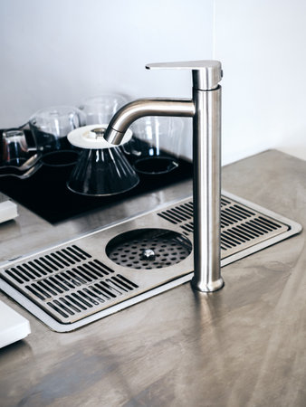 Close-up bright modern aluminium faucet at the barista counter bar in cafe, vertical style. Equipments and tools for coffee maker in coffee shop.の写真素材