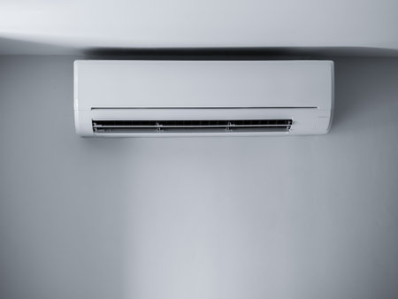 Air conditioner wall mounted decorative. Photo of white air condition hanging on clear wall background under the ceiling in empty room. Electrical wind machine equipment in house.の写真素材