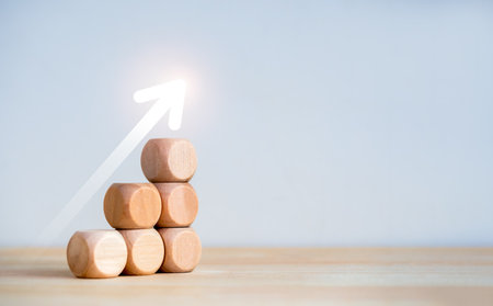 Rise up glowing arrow on wooden cube blocks as a business chart steps isolated on white background...