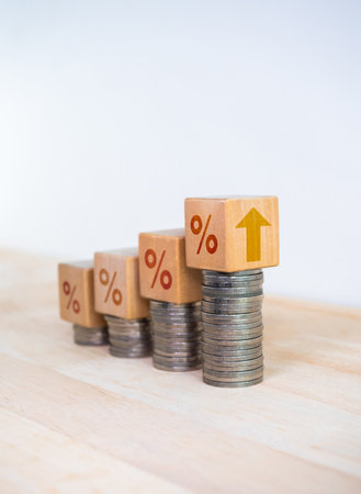 Percentage icon and up arrow on wooden cube blocks on coin stacked bar graph chart steps on white background. Investment, profit, develop income, sales, business growth, economic improvement concepts.の写真素材