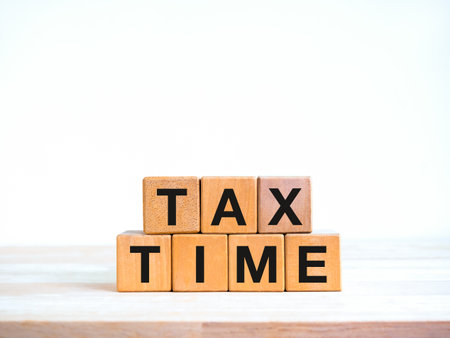 TAX TIME, text on wooden cube blocks stack isolated on wood table and white background, minimal style. Taxation, annual payment rates, income tax return, vat pay, business and finance concept.の写真素材