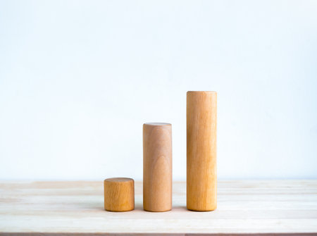 Three size of round wooden sticks as a business chart steps isolated on wood desk on white background simple style. Business growth graph process, goal, success, and economic improvement concepts.の写真素材