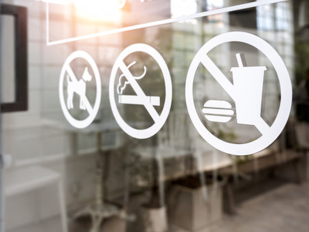Close-up of no food and drink icon, pet and no smoking forbidden sign, white sticker on glass front door of cafe or restaurant.の写真素材