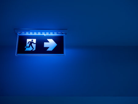 Blue tone of LED light fire escape sign hang on the ceiling in the dark building. Emergency fire exit sign, warning plate with running man icon and arrow to the right way with copy space.の写真素材