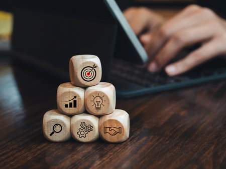 Business strategy icons on wooden cube blocks pyramid steps on desk near person work with digital tablet computer. Leadership, key success, marketing goal target process and action plan concept.の写真素材