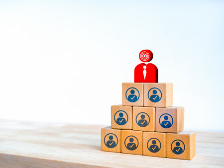 Business leadership, the leader goal, organization development concepts. Big red businessman with target icon on top of colleague or company staff on wooden blocks pyramid shape on white background.の写真素材