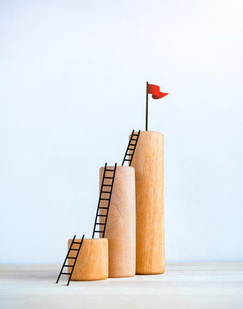 Red flag on top of wooden sticks bar graph chart steps with ladders, isolated on white background, vertical style, business market growth, effort, profit, investment, financial trend concept.の写真素材