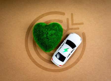 EV car, Electric energy battery charge vehicle with sustainable development concept. Electric power icon on white car near green heart-shape on target symbol on brown kraft paper background, top view.の写真素材