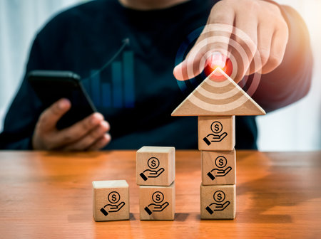Big arrowhead wooden on increase cube blocks, business growth graph with saving money icon, pointing by businessman, holding smartphone. Investment online, stock trader, digital marketing work income.の写真素材