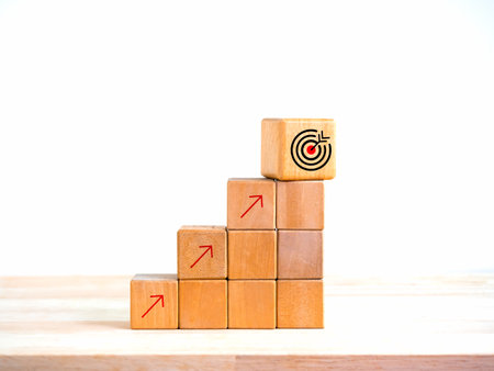 Arrow upward to the target icon symbol on wooden cube blocks, bar graph chart steps on white background, profit planning, marketing passive income, business growth process concepts, minimal style.の写真素材