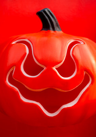 Close-up portrait of red Halloween Jack o Lantern Pumpkin with spooky smiling face. Orange pumpkin head smile face with open mouth, vertical style. Happy Halloween day minimal background concept.の写真素材
