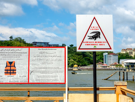 BANDAR SERI BEGAWAN, BRUNEI - APRIL 21, 2024 : Warning sign to beware of crocodiles area before crossing to Kampong Ayer, traditional village in Bandar Seri Begawan, tourism highlight landmark.のeditorial素材