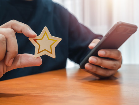 Customer review, satisfaction, feedback, survey concepts. Wooden star in person hand who use smart mobile phone for ratings to service experience and business satisfaction survey on website or app.の写真素材