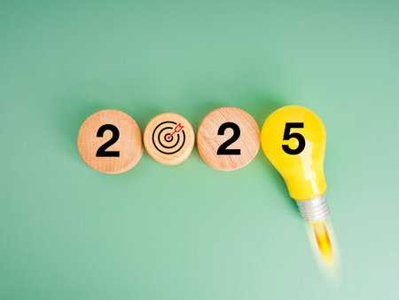 2025 new year trends and innovative technology, business startup concept. 2025 calendar numbers with target icon arranged with yellow creative light bulb flying up on green background, minimalist.の写真素材